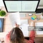 Top view of the workspace and office of a female translator working on a document and checking some references